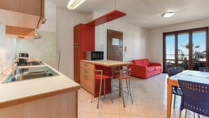 A modern kitchen with a built-in microwave, a red sofa, and a dining area with a table and chairs.