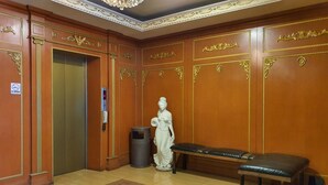 A room with a wooden wall, a statue, a bench, and a trash can. - GD Hotel - Permas Jaya (Masai)
