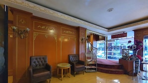 A lobby with two leather armchairs, a small round table, a staircase, and a shop visible through the doorway. - GD Hotel - Permas Jaya (Masai)