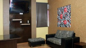 A modern living room with a flat-screen TV, a sofa, and a patterned wall decoration. - GD Hotel - Permas Jaya (Masai)