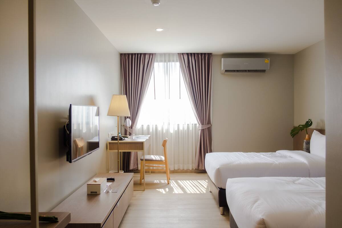 Une chambre d’hôtel équipée d’un lit, d’un bureau, d’une chaise, d’une télévision et d’un climatiseur.