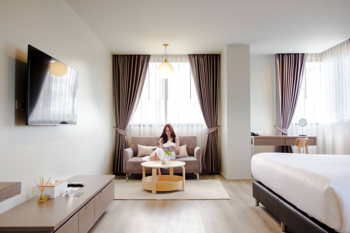 Une chambre d’hôtel moderne équipée d’un canapé, d’une table basse ronde, d’un lit, d’un bureau et d’une télévision.