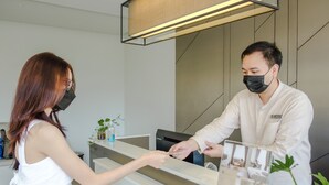 A reception area with a modern design, including a reception desk, a digital screen, and a plant. - The Rise Suites Hotel Chiang Mai  (Chiang Mai)