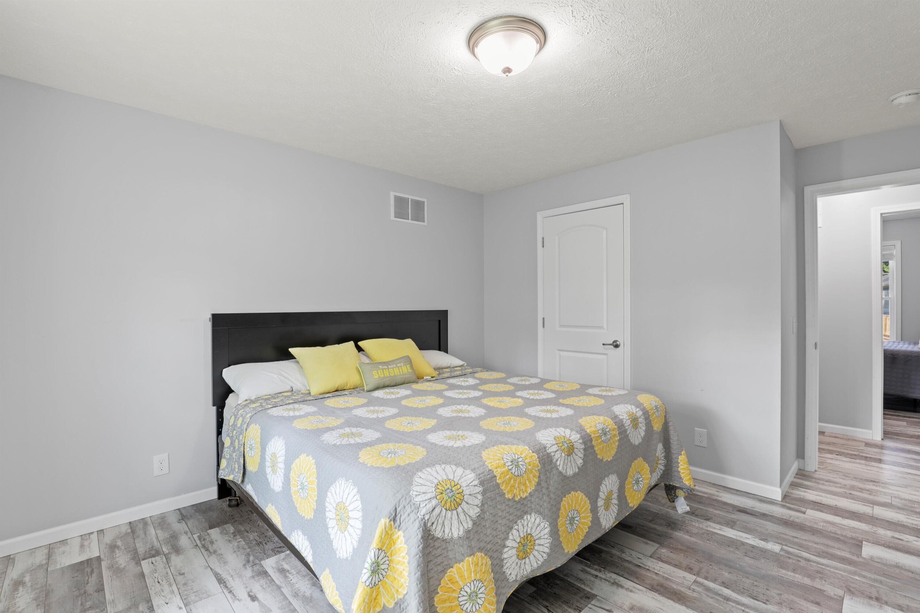 A bedroom with a bed, a door, and a hallway.