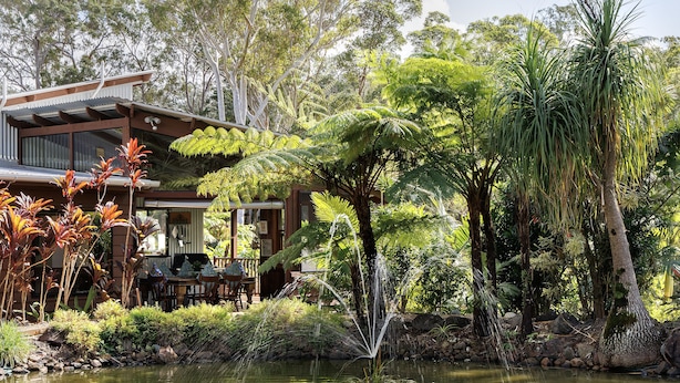 Une maison avec un jardin, un étang et un coin repas.