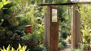 Une porte de jardin en bois agrémentée d’un miroir, entourée d’une végétation luxuriante et de différentes plantes.