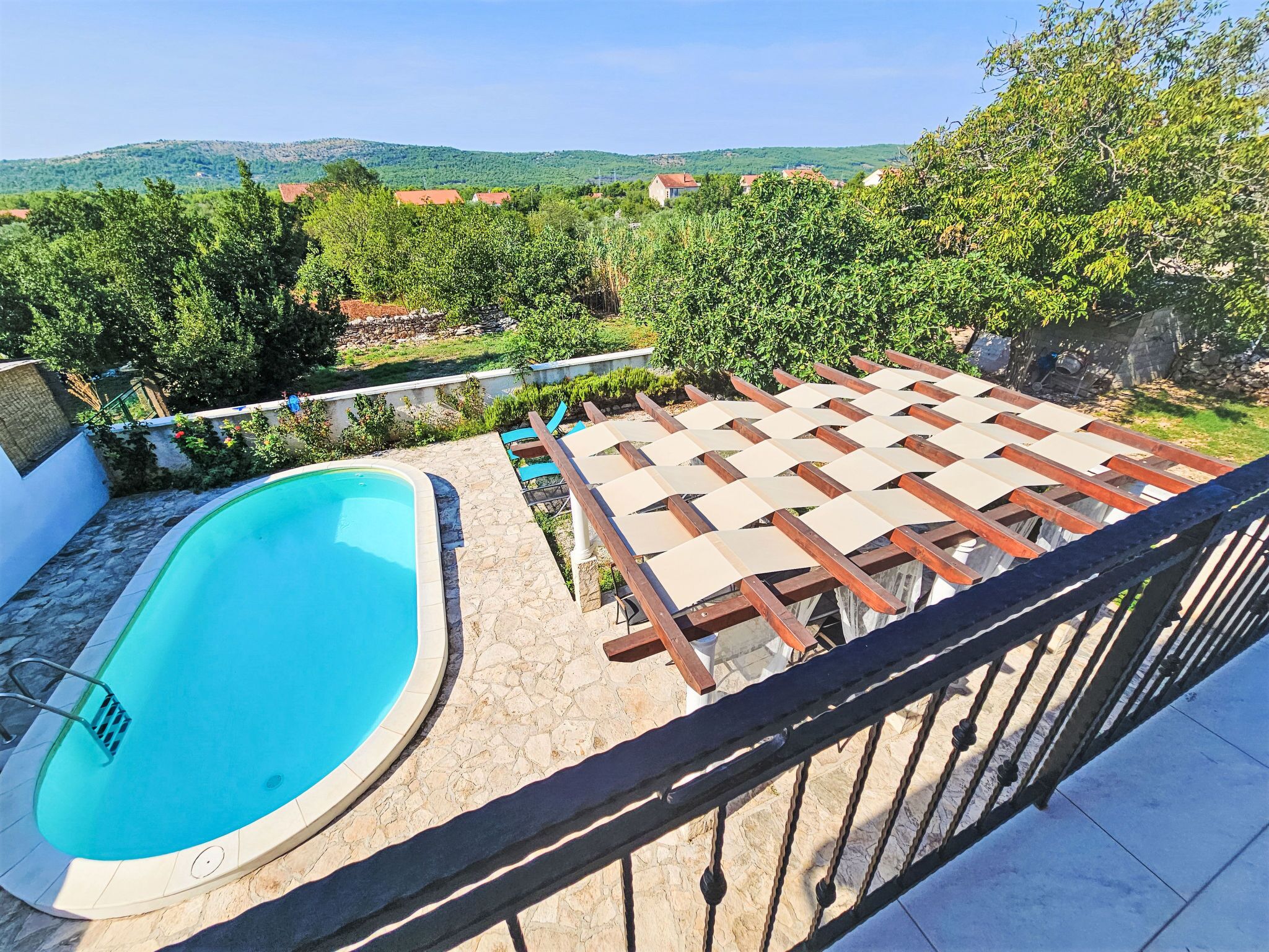 A swimming pool with a wooden deck and a view of a hillside.