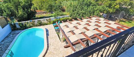 A swimming pool with a wooden deck and a view of a hillside.