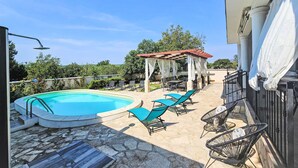A swimming pool with lounge chairs, a covered seating area, and stone flooring. - Joy on Countryside by Interhome (Šibenik/Dubrava)