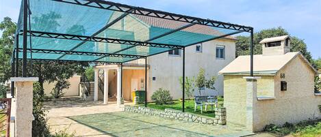Un espace extérieur abrité, doté d’une pergola, d’un chemin en pierre et d’un petit bâtiment portant le numéro 68.