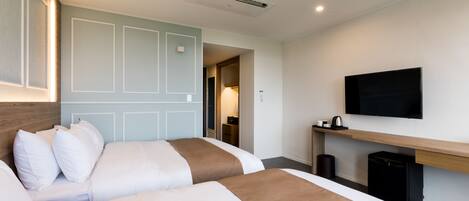 A hotel room with two beds, a television, a desk, and a trash bin.