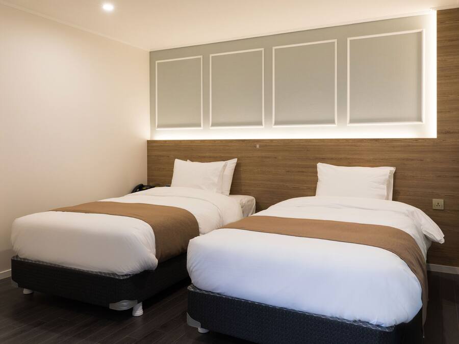 A hotel room with two beds, a wooden headboard, and a window with a view.