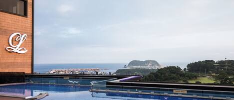 A rooftop pool with a view of the sea and a distant island.