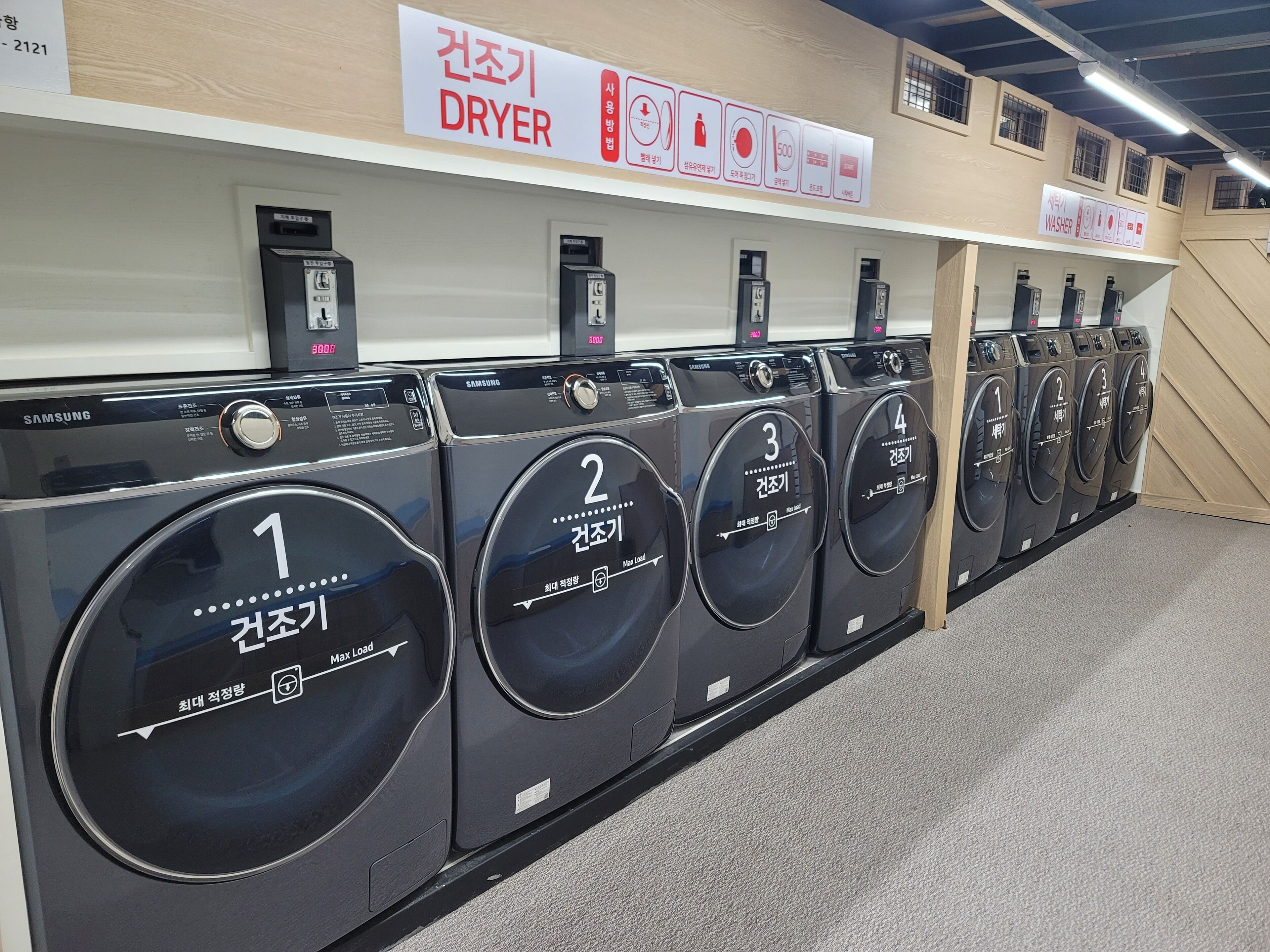 A row of black Samsung washing machines in a store, each labeled with a number from 1 to 4.