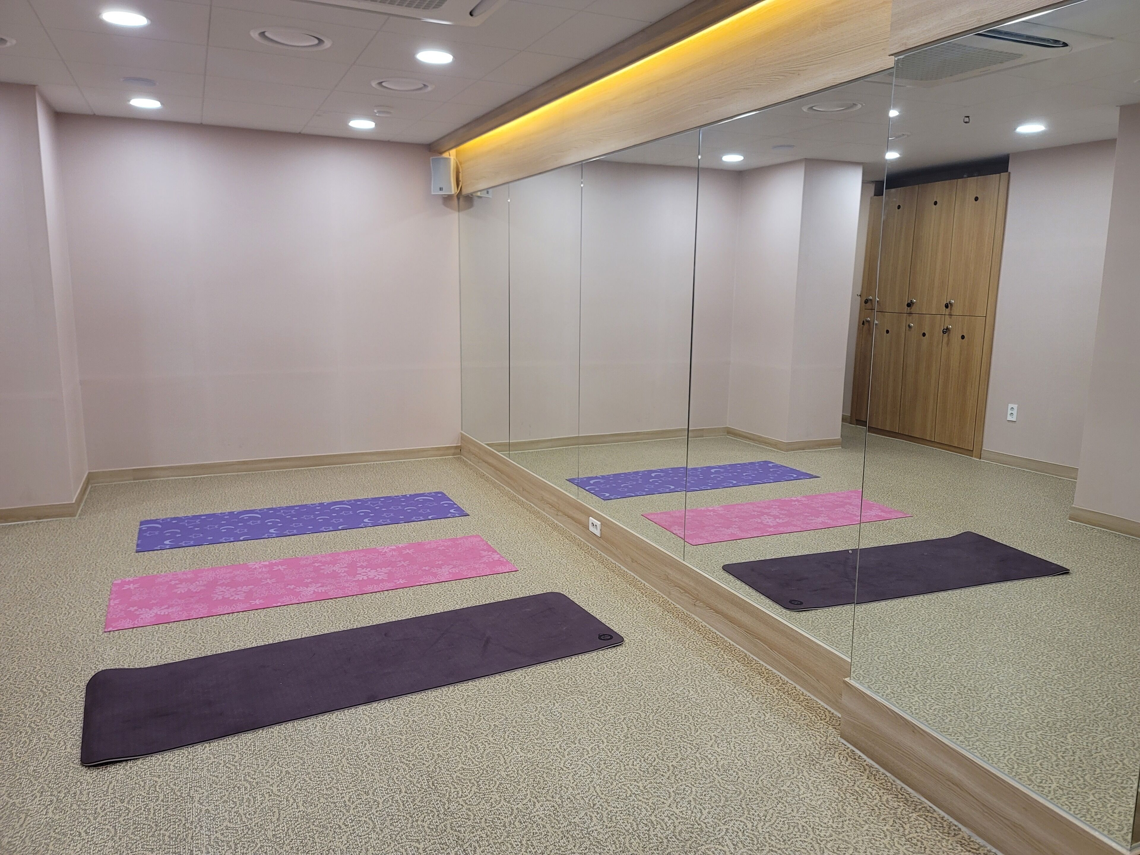 A room with a large mirror, a wooden wardrobe, and exercise mats on the floor.