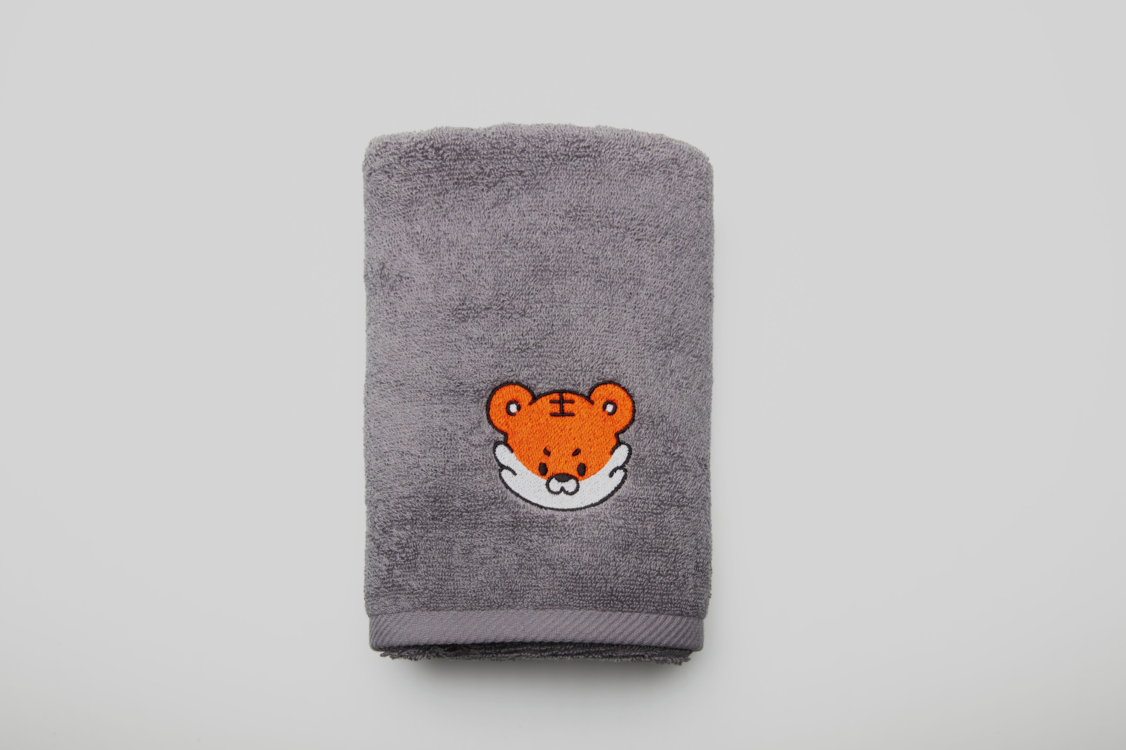 Una toalla gris doblada con un oso bordado.