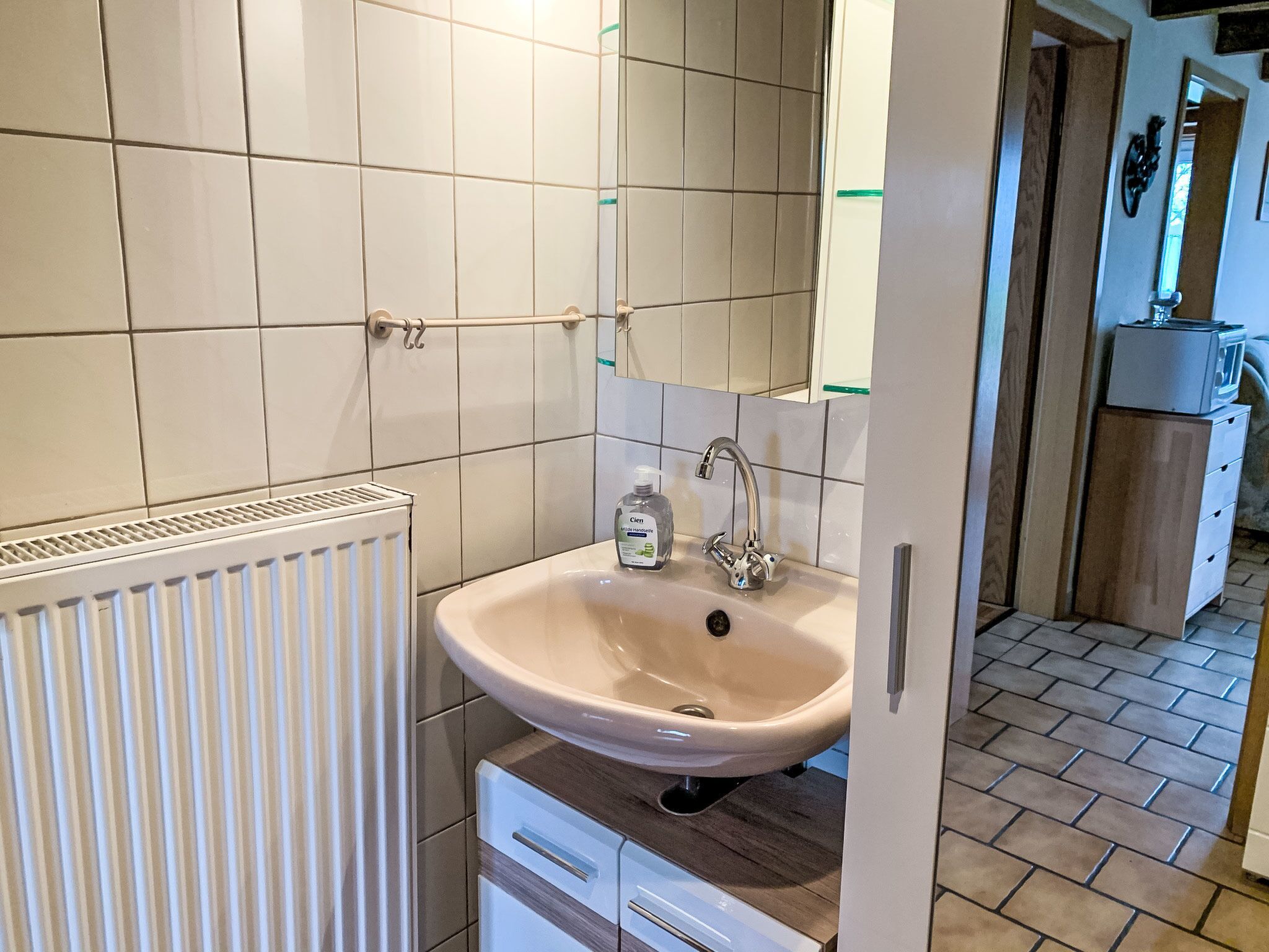 A bathroom with a white sink, a mirror, and a radiator.