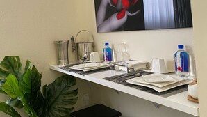 A hotel room with a white desk, a potted plant, a black stool, and a large artwork of a red rose and lips. - 🌴Luxe Oasis🌴Superhost🌴Post-Op🌴Solo & Couples Escape in Miami🌴 (Miami)