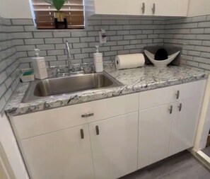 A kitchen with white cabinets, a granite countertop, a stainless steel sink, and a brick backsplash. - 🌴Luxe Oasis🌴Superhost🌴Post-Op🌴Solo & Couples Escape in Miami🌴 (Miami)