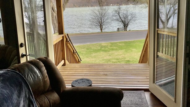 Une pièce avec vue sur un lac, une terrasse en bois et un banc.