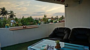 A balcony with a glass table, two black chairs, a book, and a small plant. - Hotel Nathariya Negombo (Negombo)