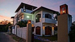 A two-story house with a gated entrance, a well-lit driveway, and a visible outdoor area with plants. - Hotel Nathariya Negombo (Negombo)
