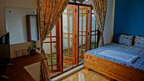 A bedroom with a bed, a wooden nightstand, a TV, and a window with curtains. - Hotel Nathariya Negombo (Negombo)