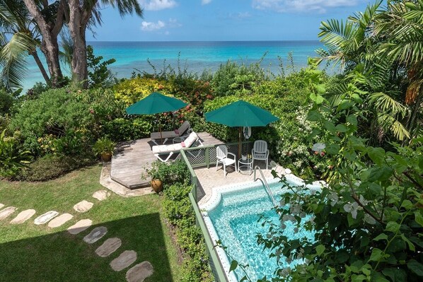 A pool area with lounge chairs and umbrellas, surrounded by lush greenery and a view of the ocean. - La Paloma by Blue Sky Luxury (Prospect)
