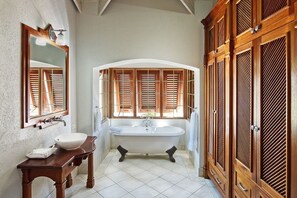 A bathroom with a freestanding bathtub, wooden cabinets, a mirror, and a sink. - La Paloma by Blue Sky Luxury (Prospect)