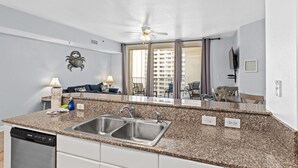 A modern kitchen with granite countertops, stainless steel sink, and a dishwasher. - 1322 Pool & Beach views, w/2 parking passes, lagoon-style pool & indoor pool (Panama City Beach)