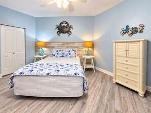 Un dormitorio con cama, dos mesitas de noche, una cómoda y un ventilador de techo.