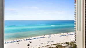A beach view from a high-rise building with a clear sky, sandy beach, and umbrellas. - 1322 Pool & Beach views, w/2 parking passes, lagoon-style pool & indoor pool (Panama City Beach)