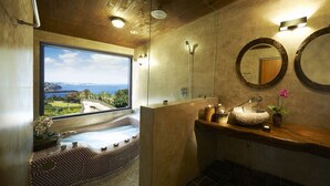 A bathroom with a large window, a stone sink, two mirrors, and a view of the sea. - Olle Resort & Spa (Jeju City)