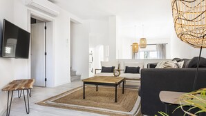 Een moderne woonkamer met een bank, een salontafel en een aan de muur bevestigde televisie.