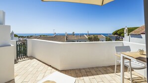 Een terras met uitzicht op zee, een tafel en een stoel.