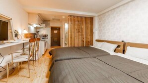 A hotel room with a bed, a desk with chairs, and a bathroom visible through a door. - Commence5 (Sapporo)
