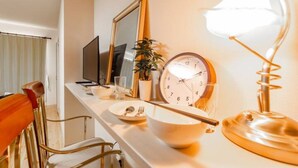 A neatly arranged dining area with a table set for two, a clock, a mirror, and a lamp. - Commence5 (Sapporo)
