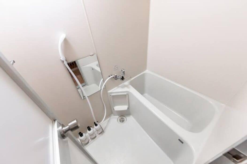A modern bathroom with a white bathtub, a small sink, and a mirror.