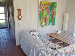 A room with a curved sofa, a wooden bench, a clock, and a colorful abstract painting on the wall. - 4 Person Holiday Home in Fano (Fano)