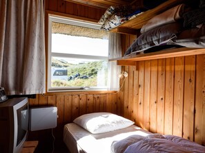 Ein kleines Zimmer mit einem Bett, einem Fenster mit Blick auf ein Fahrzeug und einem Fernseher.