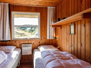 A cabin with two beds, a window with a view of a bridge, wooden walls, and a shelf with jars. - 4 Person Holiday Home in Fano (Fano)