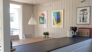 Una cocina con una isla de madera, una lámpara colgante y dos cuadros en la pared.