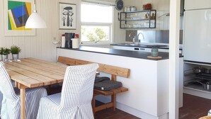 Una cocina compacta con una mesa y banco de madera, un lavamanos y un refrigerador.