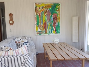A room with a sofa, a wooden table, a wall clock, and a colorful abstract painting.