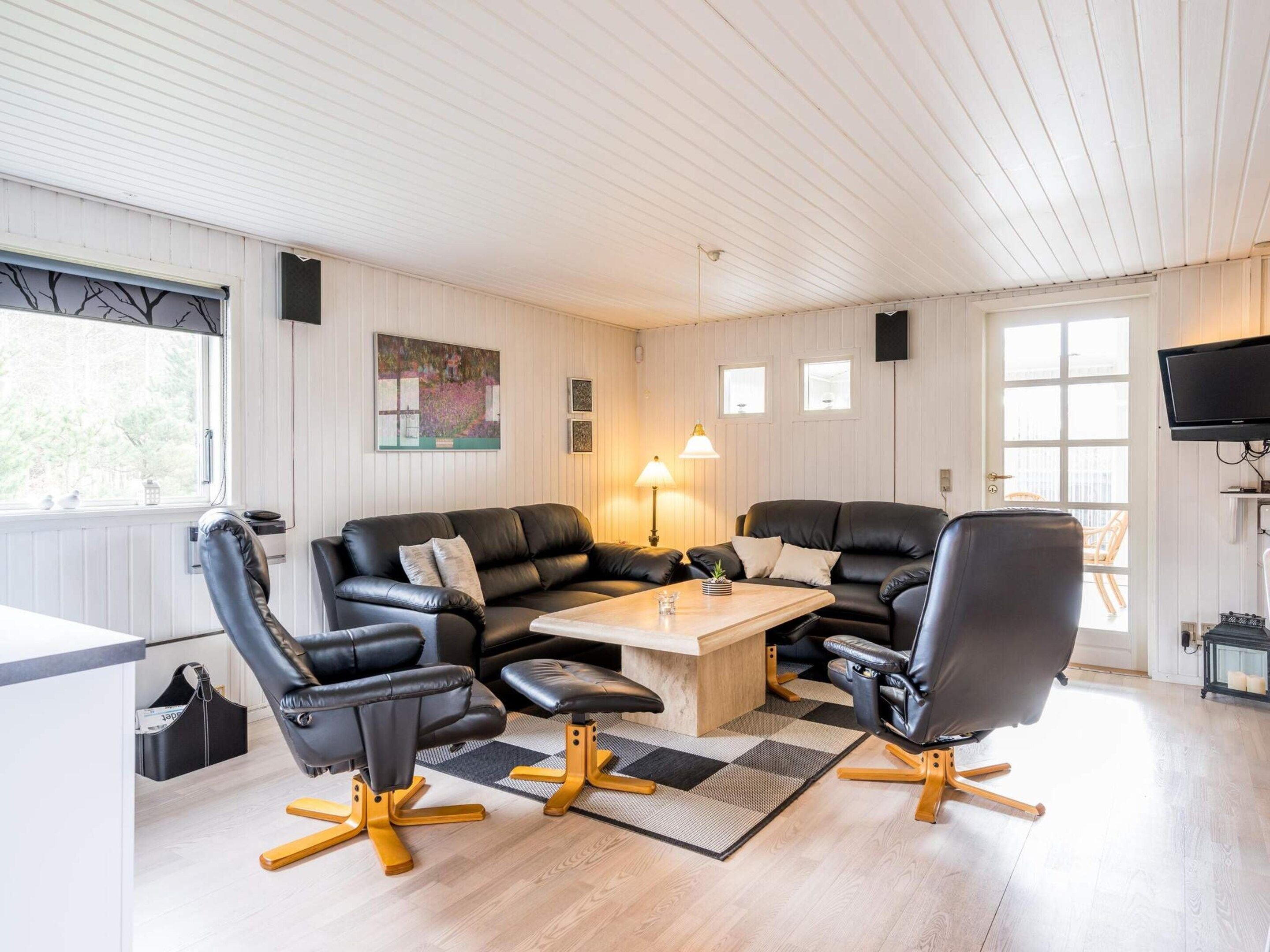 A modern living room with a sectional sofa, two armchairs, a coffee table, and a television.