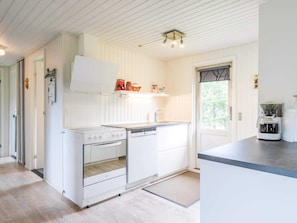 A kitchen with white cabinetry, a stove, a dishwasher, and a coffee maker.