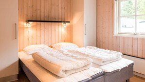 A bedroom with a bed, wooden walls, a window, and a shelf with lights. - 5 Star Holiday Home in Blavand (Blavand)