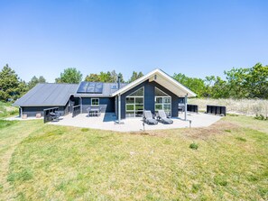 A modern house with a large garage, outdoor seating area, and a covered patio. - 5 Star Holiday Home in Blavand (Blavand)