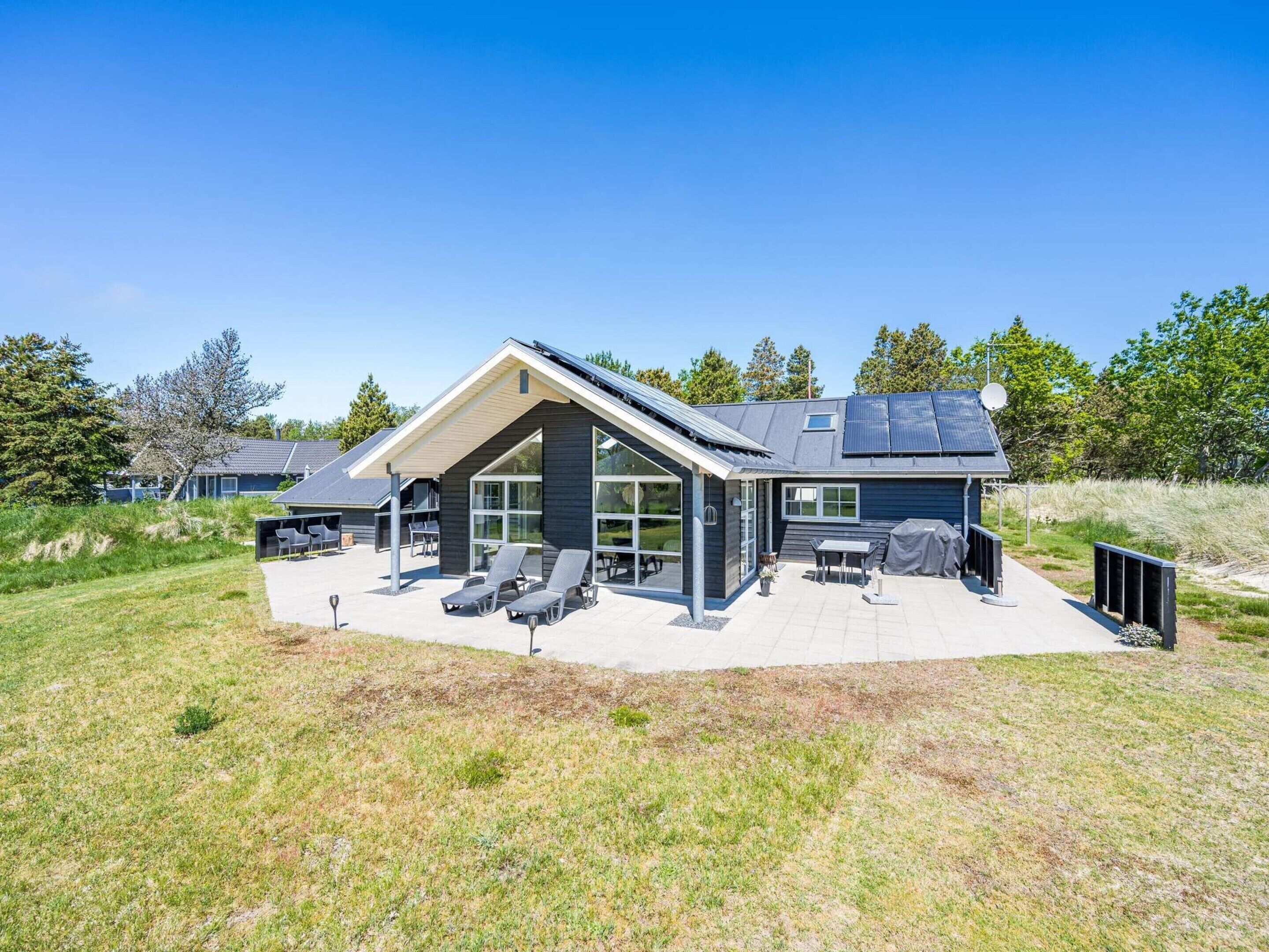 A modern house with a large patio, solar panels, and a covered outdoor seating area.