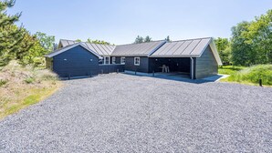 A two-story building with a gravel driveway and a covered outdoor area. - 5 Star Holiday Home in Blavand (Blavand)
